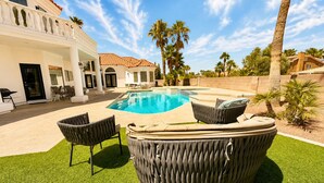 Une piscine avec un jacuzzi, du mobilier d’extérieur et des palmiers.