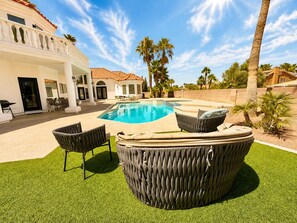 Una piscina con hidromasaje, mobiliario exterior y palmeras.