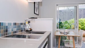Una cucina moderna con una grande isola, un'area pranzo con tavolo e sedie, e vista sul giardino tramite una porta in vetro.