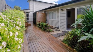 Una casa moderna con una veranda in legno, un piccolo giardino e un garage.