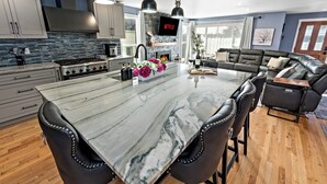 A modern kitchen with a large island, black leather chairs, and a fireplace. - 5-Bedroom · Rooftop · Game Room · Sleeps 11 · Lake View (Seattle)