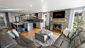 A modern living room with a fireplace, a large TV, and a cozy seating area. - 5-Bedroom · Rooftop · Game Room · Sleeps 11 · Lake View (Seattle)