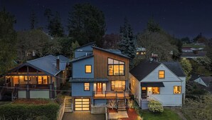 A modern two-story house with a covered porch, a small garden, and a clear night sky. - 5-Bedroom · Rooftop · Game Room · Sleeps 11 · Lake View (Seattle)