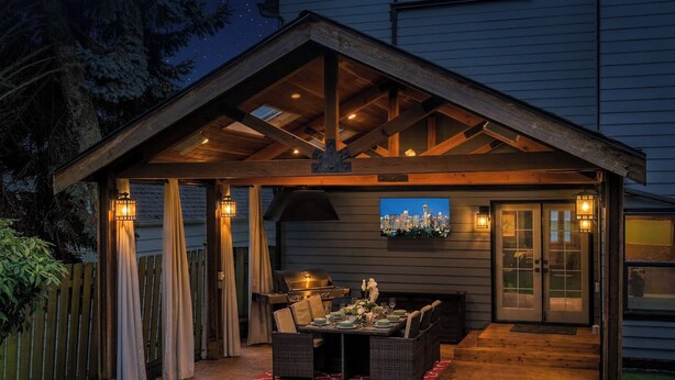 An outdoor patio with a grill, dining table, and chairs, under a covered area with a cityscape view. - 5-Bedroom · Rooftop · Game Room · Sleeps 11 · Lake View (Seattle)