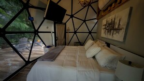 A modern bedroom with a geometric ceiling design, a bed with white bedding, and a painting on the wall. - Domo Las Flores: Eco-Luxury Glamping, Heated Saltwater Pool & Solar Power (Coamo)