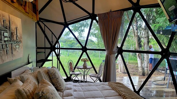 Een kamer met een groot bed, uitzicht op de omgeving en een geometrisch plafond.
