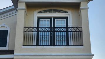 Een tweelaags huis met een witte garage deur, een balkon met zwarte hekwerken en een decoratief raam boven de deur.