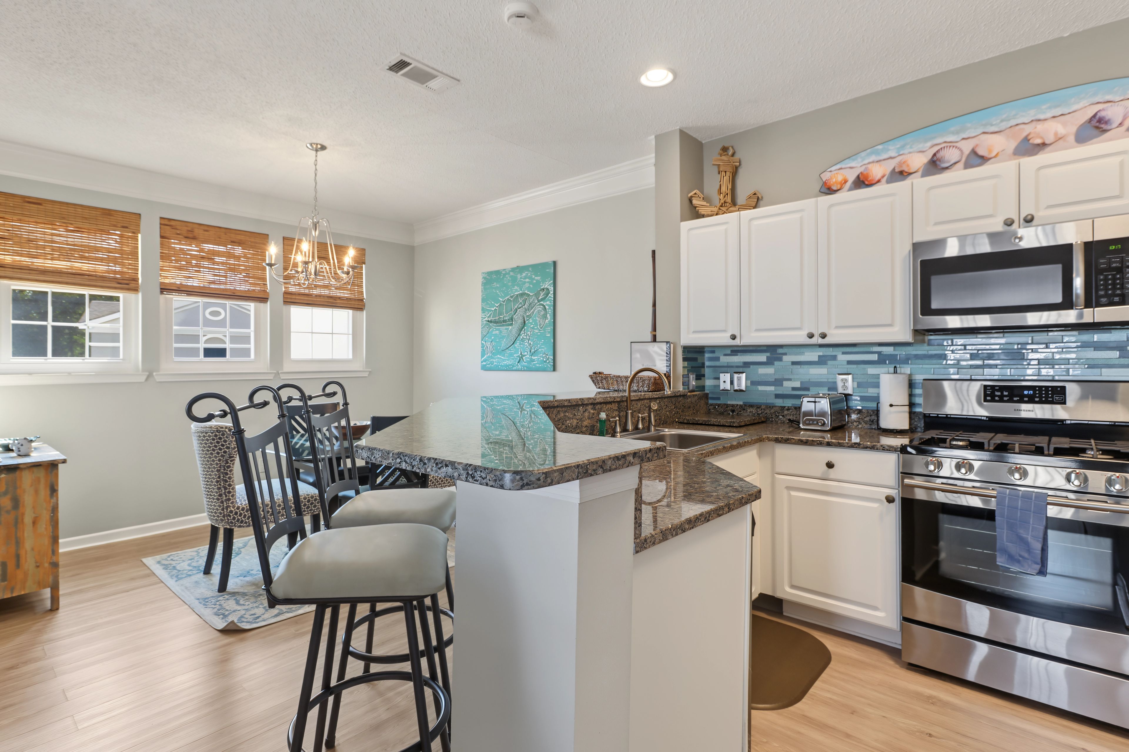 A modern kitchen with a central island, stainless steel appliances, and a dining area with bar stools.