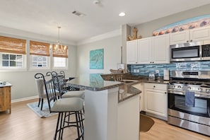 A modern kitchen with a central island, stainless steel appliances, and a dining area with bar stools.