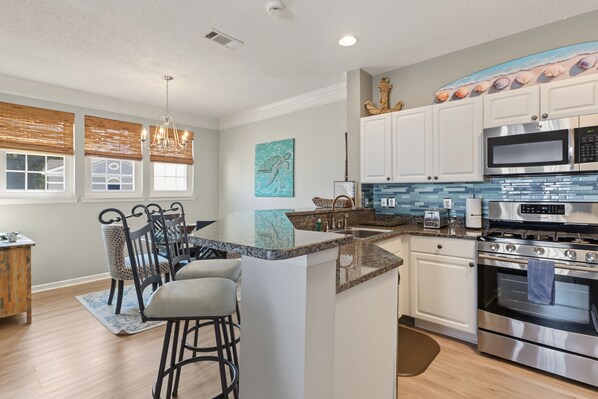 A modern kitchen with a central island, stainless steel appliances, and a dining area with bar stools.