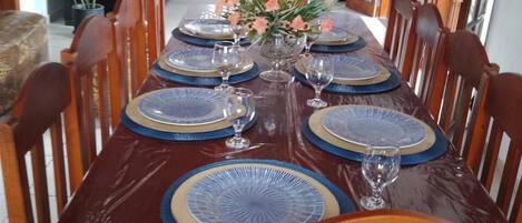 A dining table set with blue and gold plates, surrounded by wooden chairs.