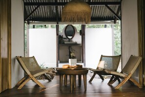 A room with two wicker chairs, a round wooden table, and a hanging light fixture. - El Tumbo de las Olas (Puerto Jiménez)