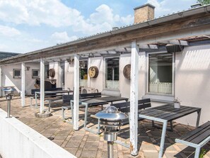 Ulkoterassi, jossa on pergola, istuimia ja grilli.