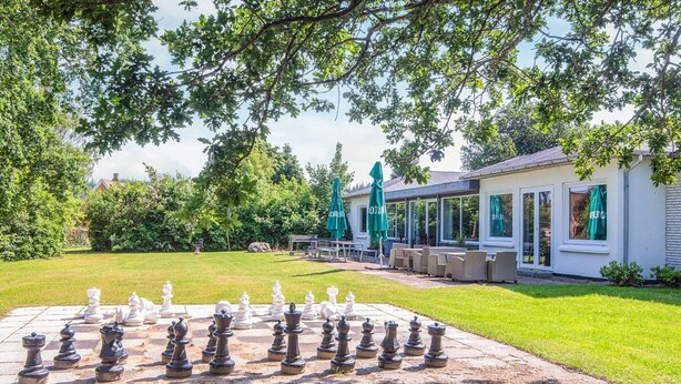 A chessboard set up outdoors with a building in the background. - Lush Cabin in Camping Resort (Aabenraa)