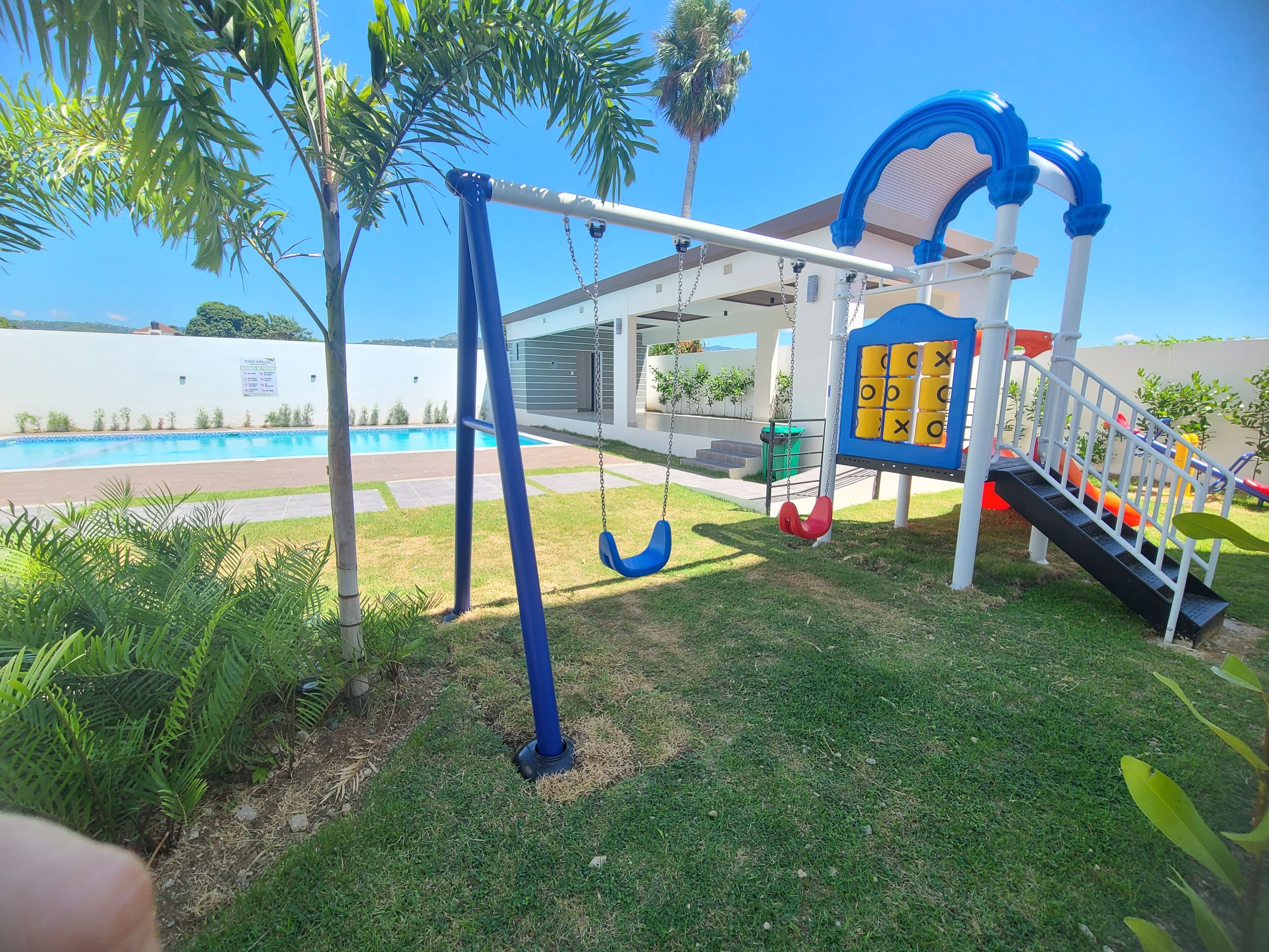 A playground with swings, a slide, and a tic-tac-toe game board.