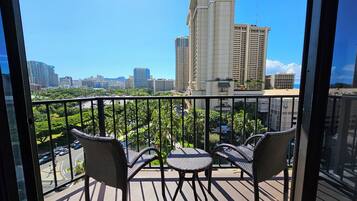 A balcony with wicker furniture and a city view.
