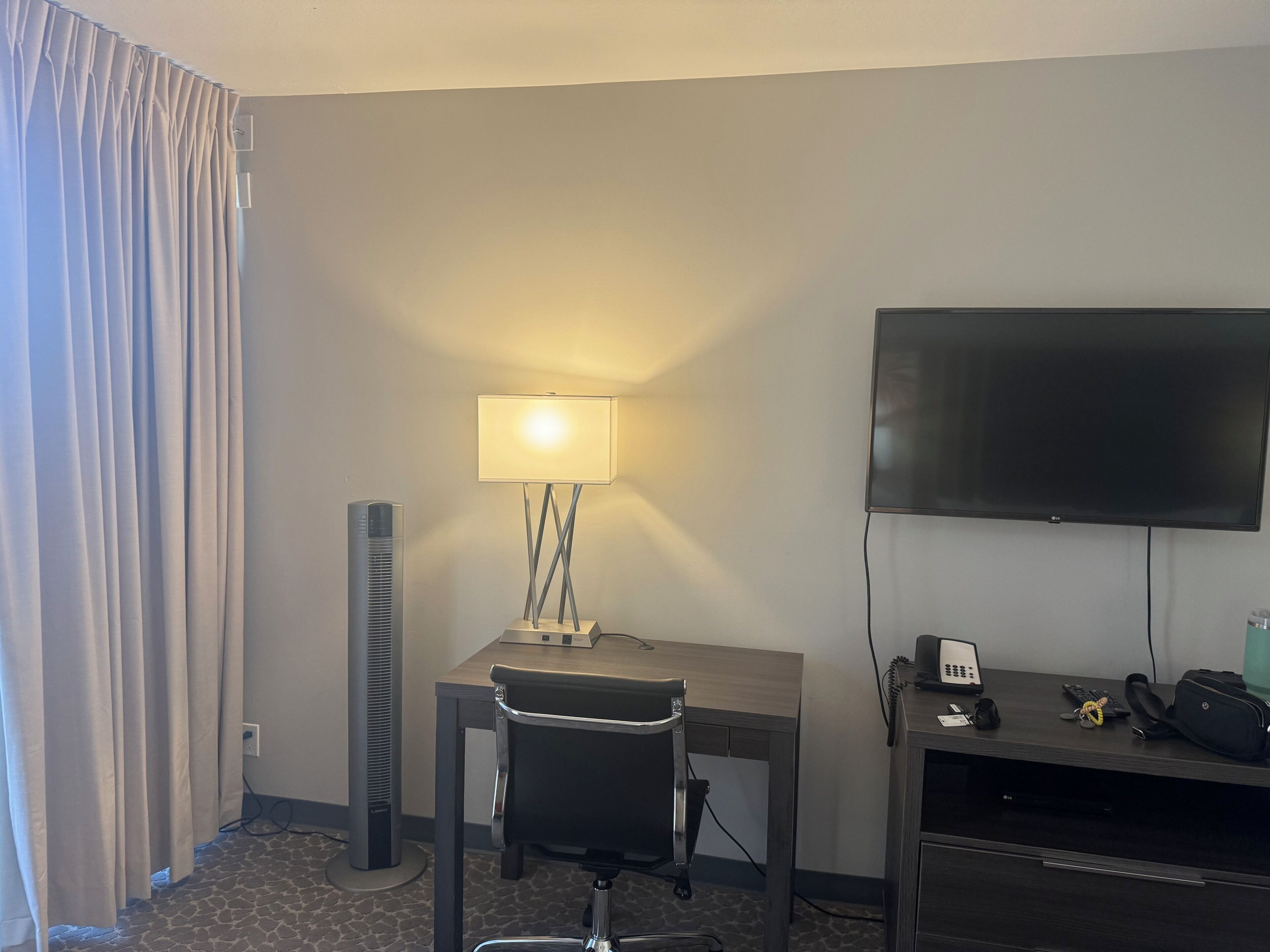 Une chambre d’hôtel équipée d’un bureau, d’une chaise, d’une lampe, d’une télévision et d’un téléphone.