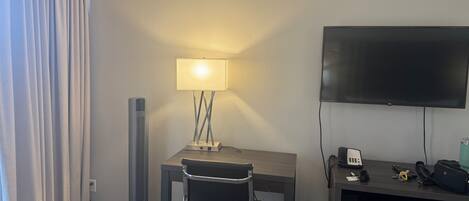 Une chambre d’hôtel équipée d’un bureau, d’une chaise, d’une lampe, d’une télévision et d’un téléphone.