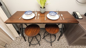 Een eettafel met twee stoelen, een bloempot en een telefoon.