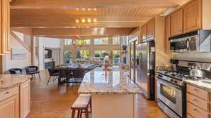 A spacious kitchen with wooden cabinets, granite countertops, and stainless steel appliances. - Lakeside Escape – Beach Access, Heated Pool, Hot Tub & Sunset Views (Lakeside)