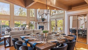 A spacious dining area with a large wooden table set for six, surrounded by dark upholstered chairs. - Lakeside Escape – Beach Access, Heated Pool, Hot Tub & Sunset Views (Lakeside)