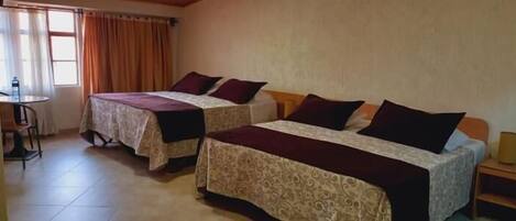 A hotel room with two beds, a small table, and a chair.