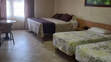 A room with two beds, a table, and a chair.
