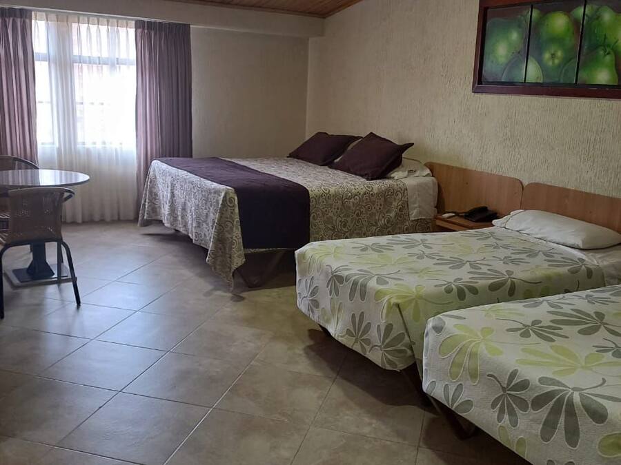 A room with two beds, a table, and a chair.