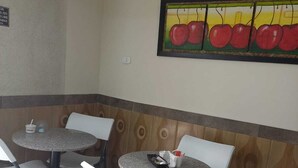 A small dining area with four tables and chairs, a tiled floor, and a wall mural of apples. - Hotel Casa Colonial  (Bogotá)
