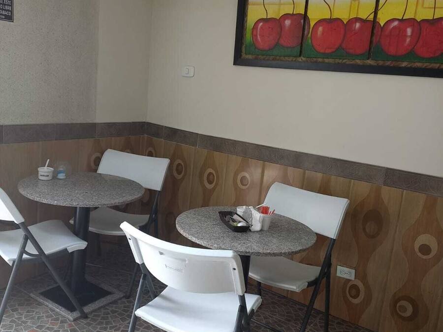 A small dining area with four tables and chairs, a tiled floor, and a wall mural of apples.