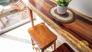 A wooden table with a potted plant, a woven placemat, and a wooden stool. - NHOA 205A 2BR Condo Pool View Aldea Zama (Tulum)