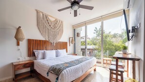 A spacious bedroom with a large bed, wooden headboard, and a ceiling fan. - NHOA 205A 2BR Condo Pool View Aldea Zama (Tulum)