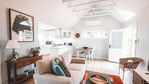 Un amplio espacio de estar con un sofá, una consola de madera y una mesa de comedor.