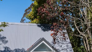 Una casa con fachada gris, una puerta principal blanca y un pequeño porche.