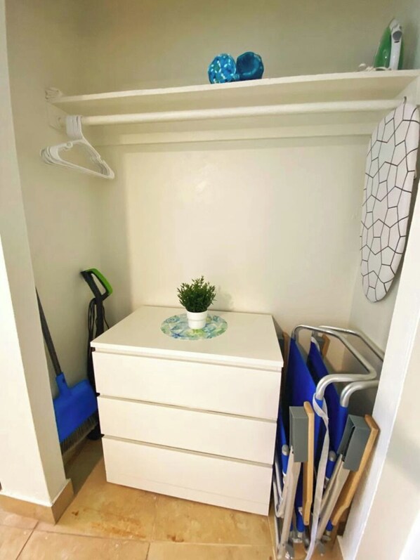 Un meuble de rangement compact agrémenté d’une petite plante en pot, d’une étagère suspendue et d’une étagère en métal où sont disposés des objets bleus.