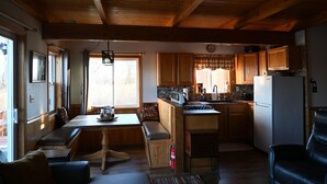 A cozy cabin interior with a dining area, kitchen, and seating space. - The Denali View Cabin (Trapper Creek)
