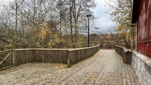 A wooden boardwalk with a metal railing, surrounded by trees with autumn leaves. - 4 Star Holiday Home in Gnesta (Gnesta)