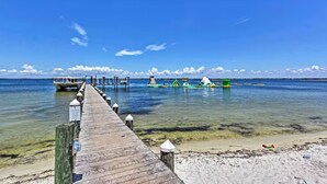 A wooden pier leading to a beach with clear water and a boat docked at the end. - Emerald of the Gulf - beachfront condo at Portofino Island resort, great views! (Pensacola Beach)