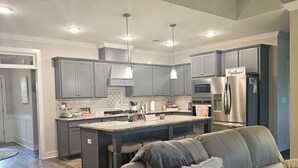 A modern kitchen with grey cabinets, a central island, and a stainless steel refrigerator. - Masters Tournament Rental 2027 (Graniteville)