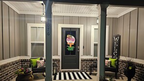 A porch with a black door, two white-framed windows, a welcome sign, and a striped rug. - Masters Tournament Rental 2027 (Graniteville)