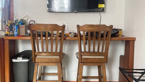 A room with two wooden chairs facing a desk with a flat-screen TV mounted above it. - Charming 2-bedroom cabin with WiFi and AC in Licking (Licking)