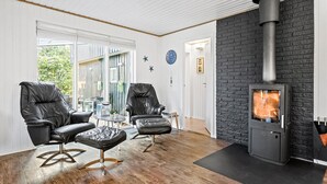 A modern living room with a black brick fireplace, leather chairs, and a glass table.