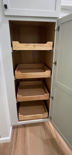 Ein Schrank mit drei offenen Einlegeböden und einer Tür.