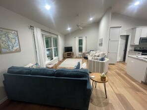 A modern living room with a sofa, a television, and a dining area with a table and chairs.