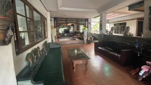 A spacious room with a long green sofa, a small table, and a motorcycle. - Hotel Candra Adigraha (Denpasar)