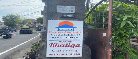 Un cartel de hotel con el nombre 'CANDRA ADIGRAHA' y el número de contacto para servicios de catering.
