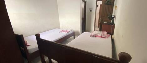 Una habitación pequeña y sencilla con una cama individual, una silla de madera y una mesita.