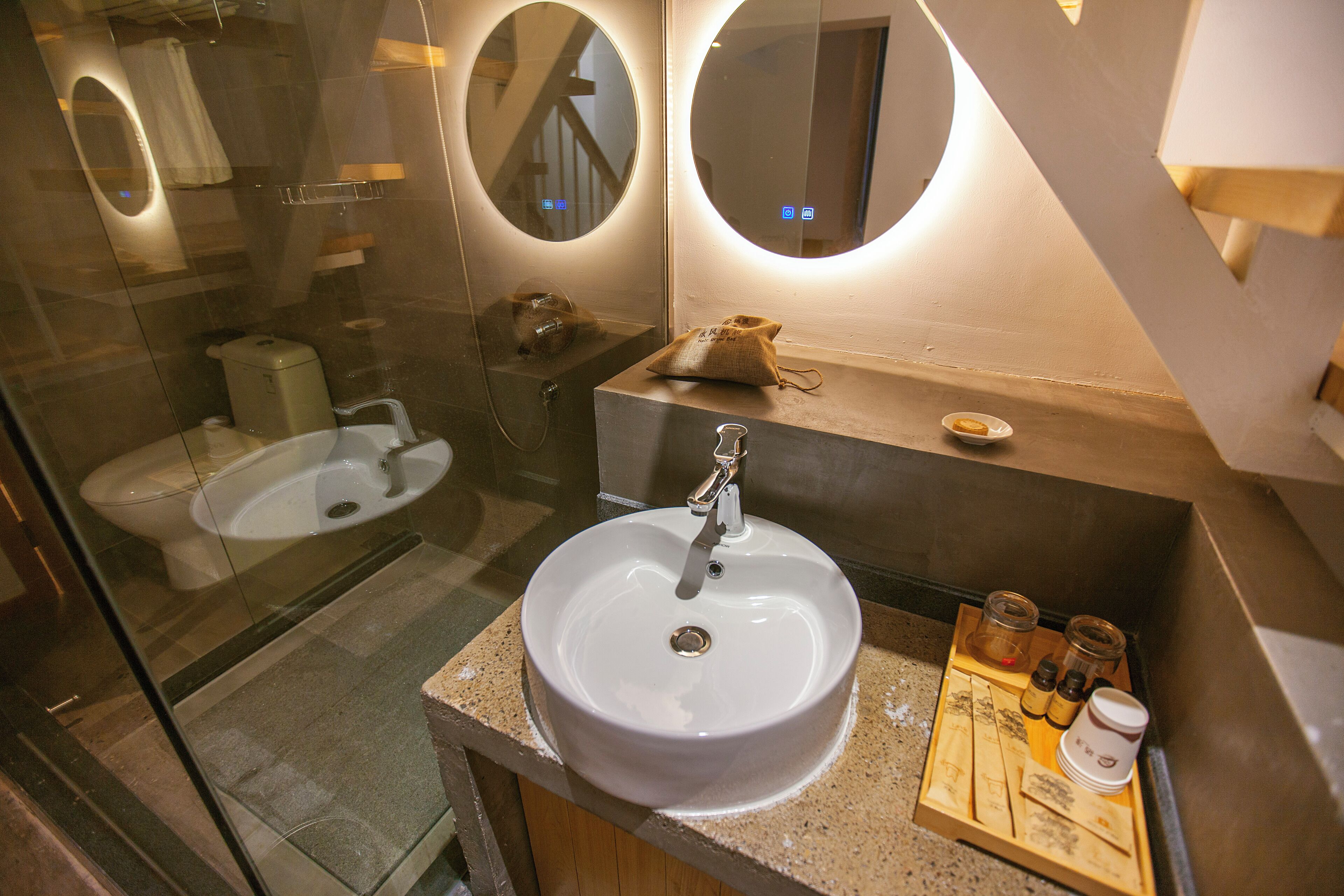 Een moderne badkamer met een grote wastafel, een spiegel en een klein houten dienblad met toiletartikelen.