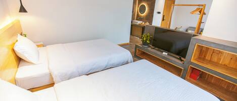 Habitación de hotel con dos camas, un televisor, un espejo y un aparador de madera.