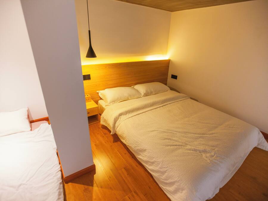 A bedroom with a wooden headboard, a white bedspread, and a bedside table with a lamp.